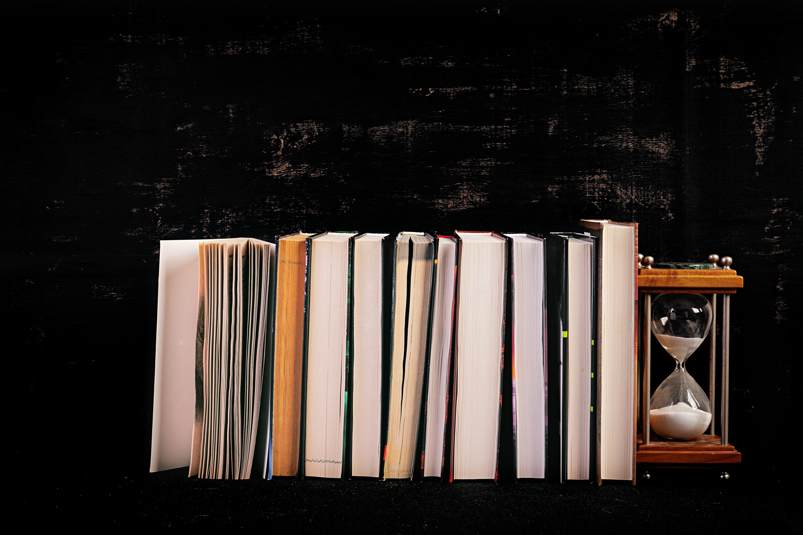 Stack of different books on dark background.